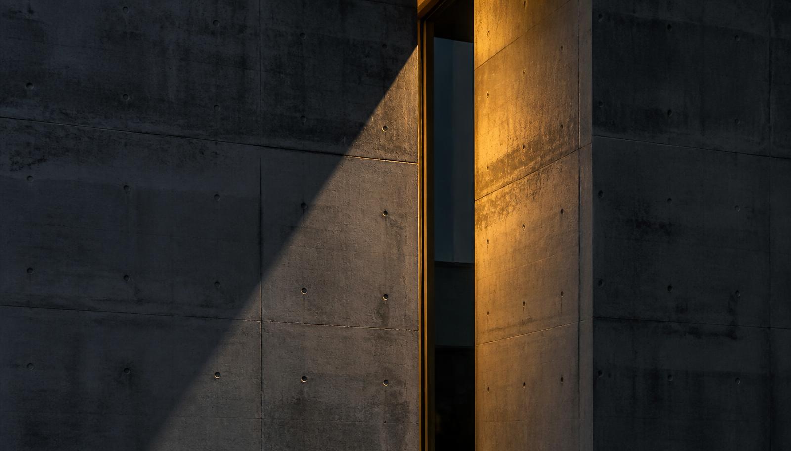 Detalhe arquitetônico de concreto aparente com luz dourada rasante